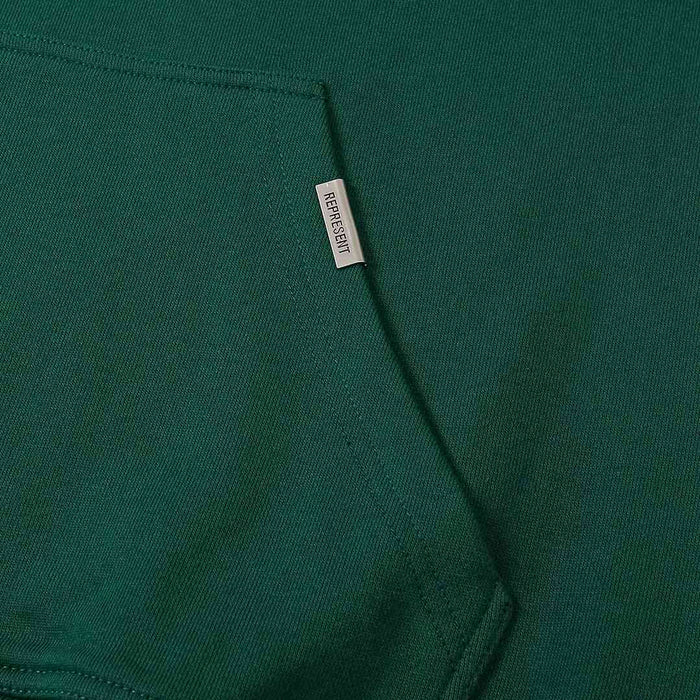 Green hoodie with small fabric label tag at side seam
