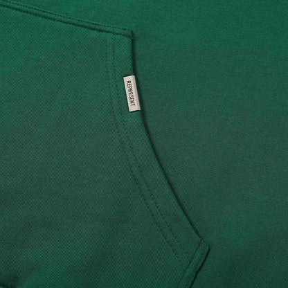 Green hoodie side seam with small brand label tag