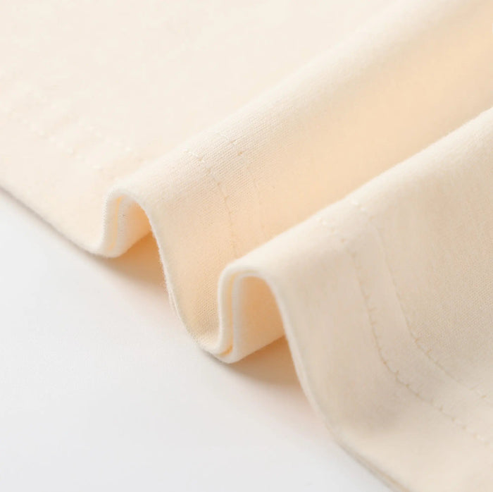 Cream T-shirt fabric close-up with folded hem edge