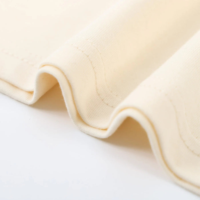 Beige T-shirt fabric close-up with stitched seam and folded hem edge