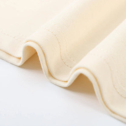 Beige T-shirt fabric close-up with stitched seam and folded hem edge