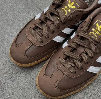 Close-up of brown Samba sneakers with adidas logo, gold accents, white stripes