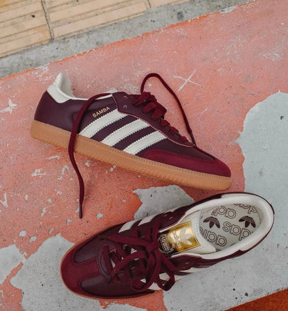 Adidas Samba OG pair of maroon sneakers with white stripes, lace-up fronts, and gum soles
