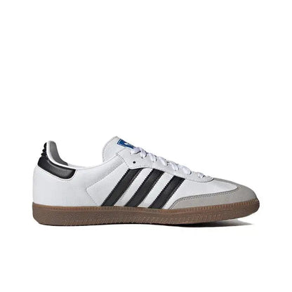 White Adidas Samba vegan sneakers with black stripes, blue tongue tag, and gum sole.
