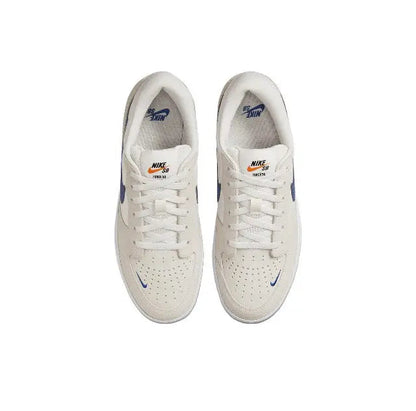 Low-top skate shoes front view, white laces on cream upper with blue accents.