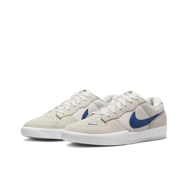 Low-top skate shoes side view, cream leather with blue Swoosh and white sole.