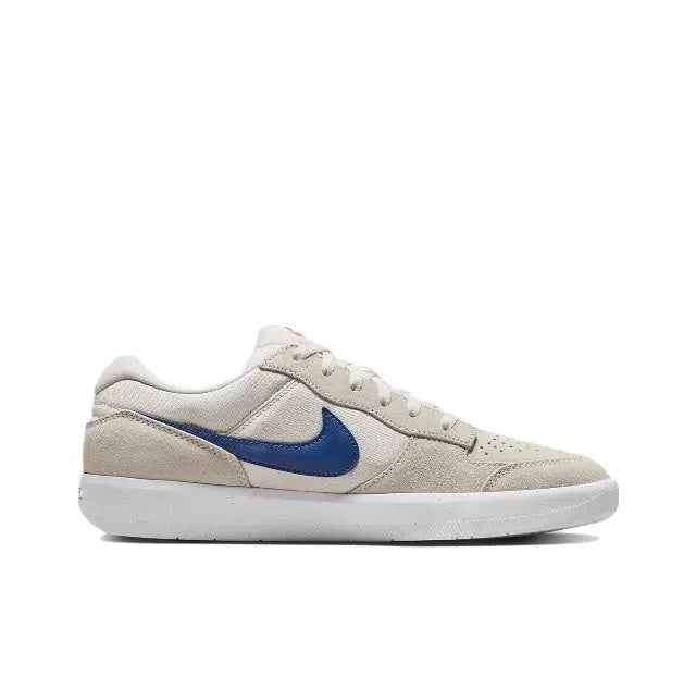 Low-top skate shoes side profile, cream upper with blue Swoosh and lace-up front.
