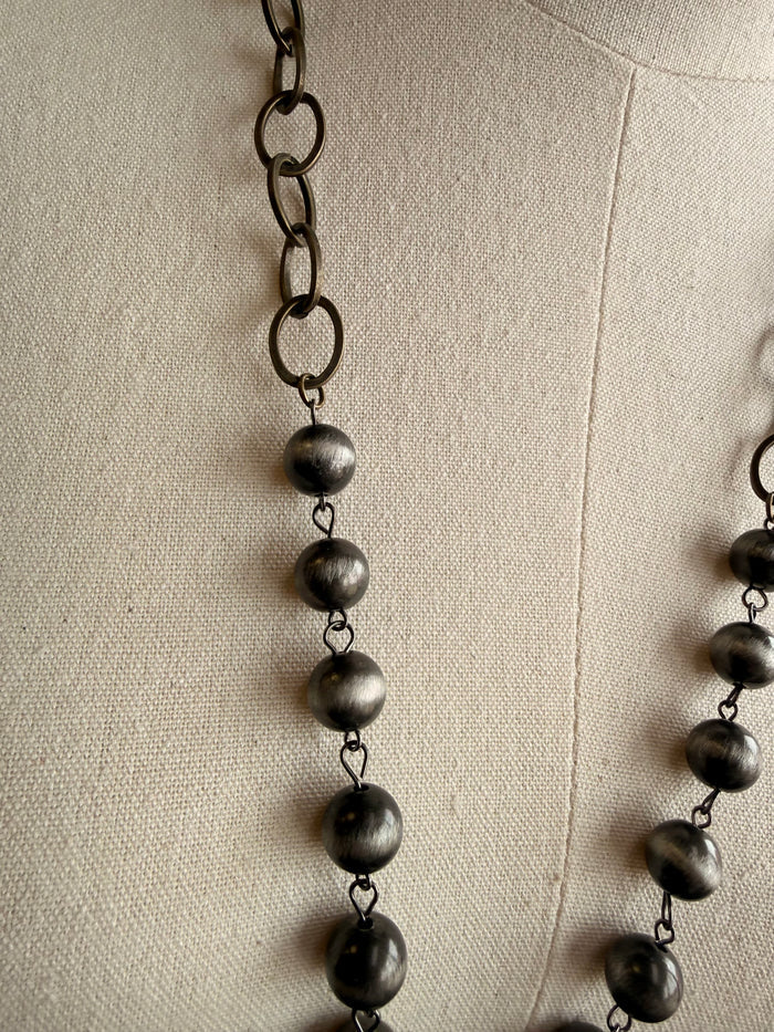 Dark bead pendant necklace with linked chain and five dangling spheres