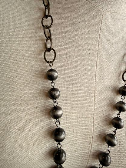 Dark bead pendant necklace with linked chain and five dangling spheres