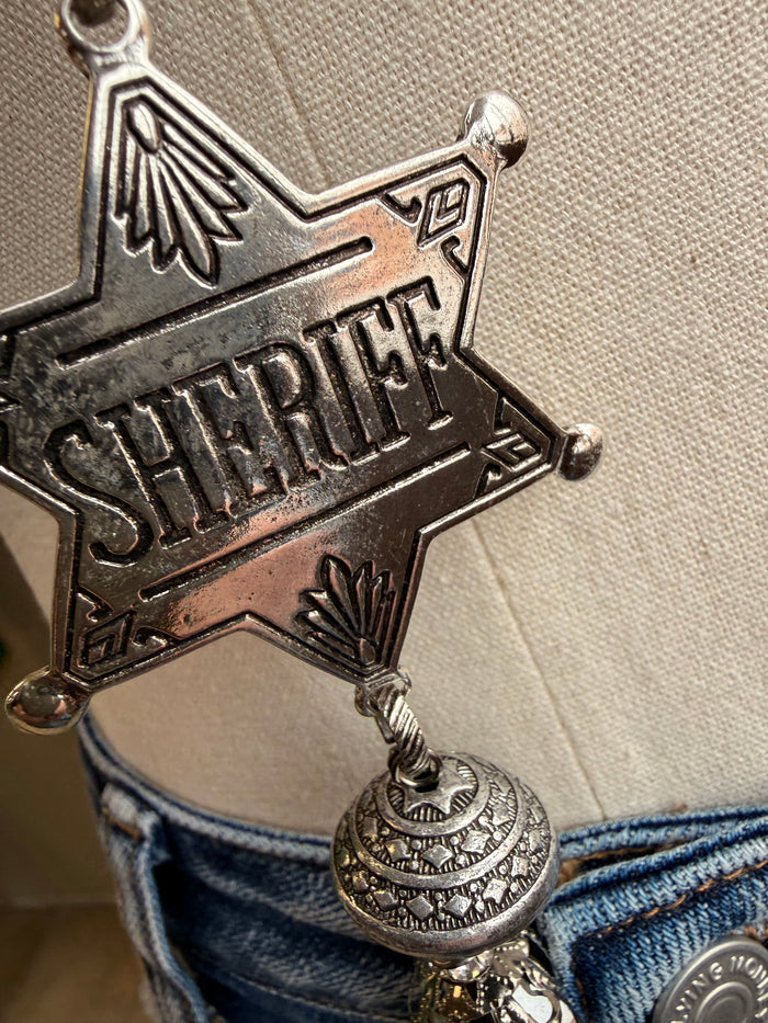 Close-up silver sheriff star pendant with ornate stamped details and bail