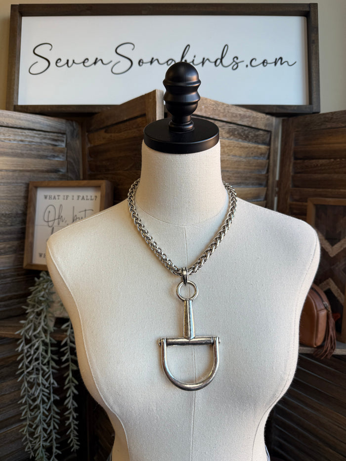 Silver chain necklace with snaffle bit pendant hanging at center