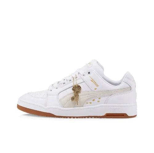 White Puma low-top sneakers with gum sole and gold accent lace graphic