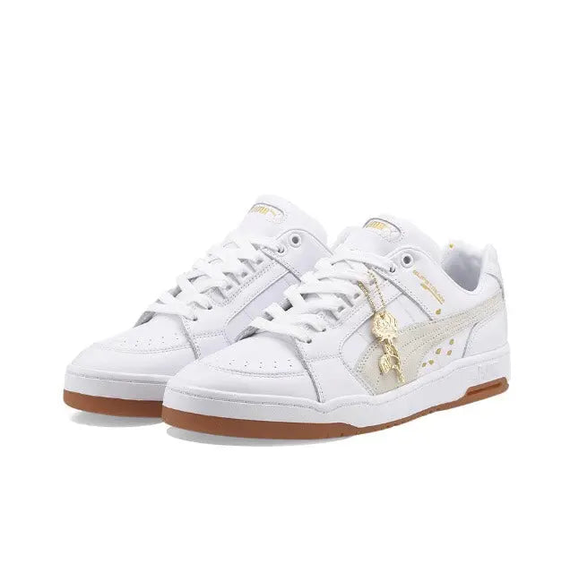 Pair of white Puma low-top sneakers with gold side stripe and lace