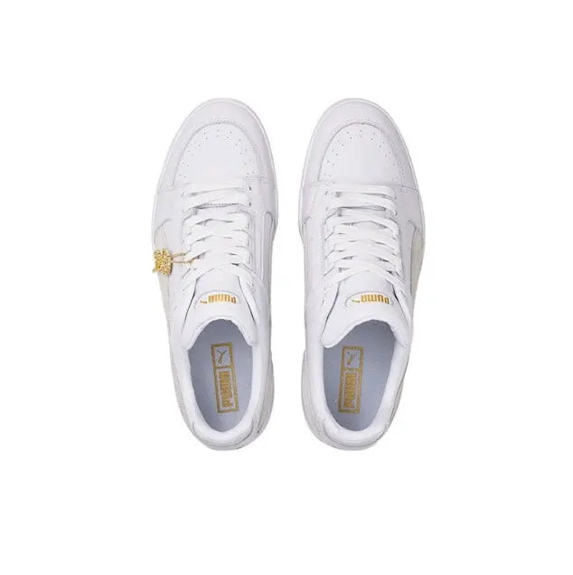 White Puma low-top sneakers, front view, with lace and gold logo detail