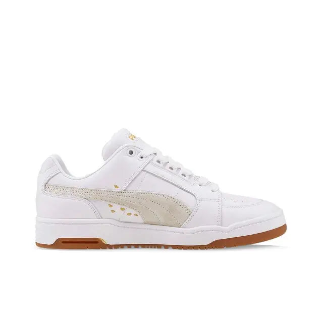 White Puma low-top sneakers with beige side panel, gold stripe, and gum sole