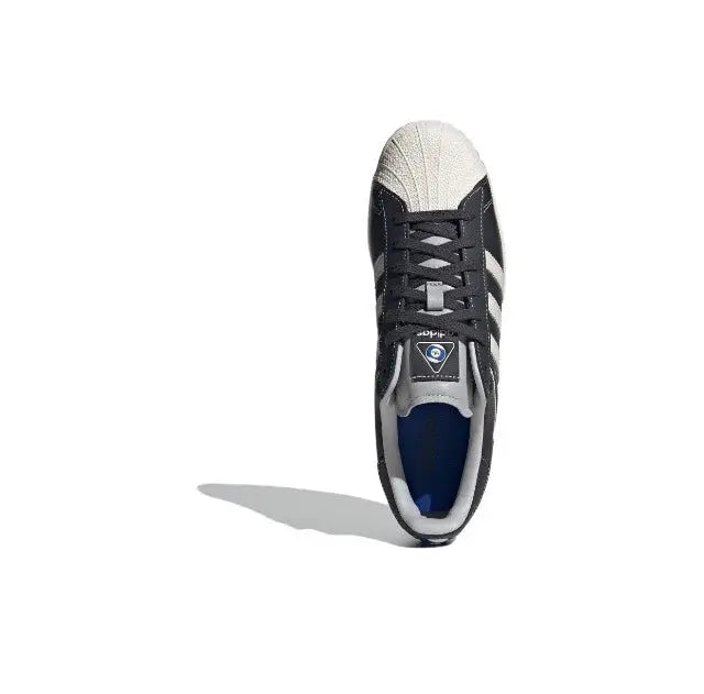 Adidas Superstar sneaker heel and toe view, dark carbon upper with blue lining