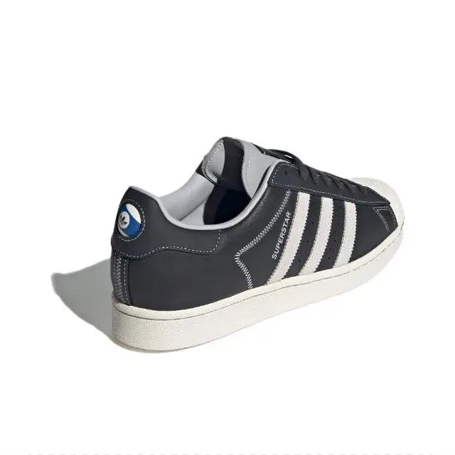 Adidas Superstar sneaker side view, dark carbon leather with white triple stripes
