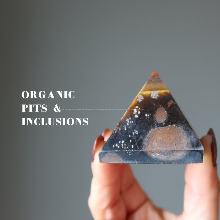 hand holding Tigers Eye Pyramid showimg organic pits and inclusions