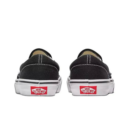 Vans Slip On black canvas sneakers with Vans heel label and white rubber sidewalls, back view.