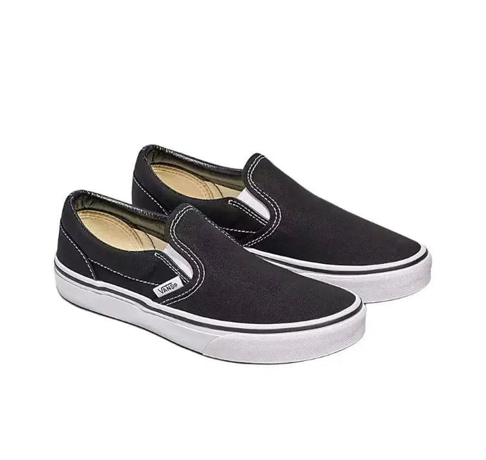 Vans Slip On black canvas sneakers with white rubber sole and loop tab, angled top view.