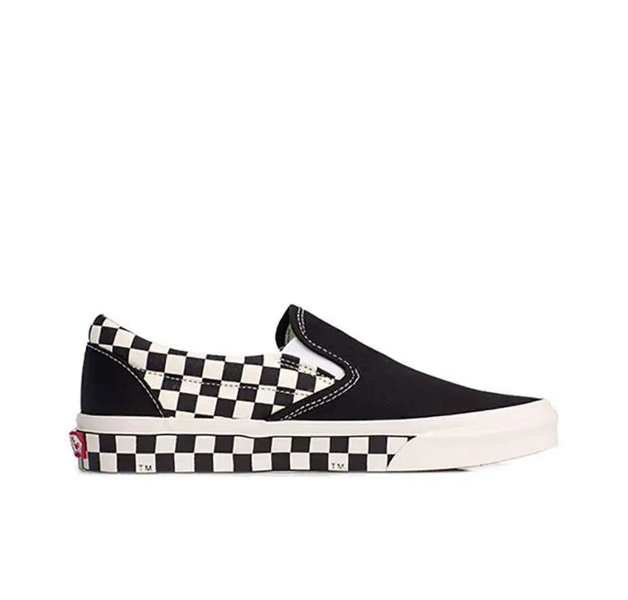Vans slip-on sneaker side view, black canvas with checkered strap and white outsole