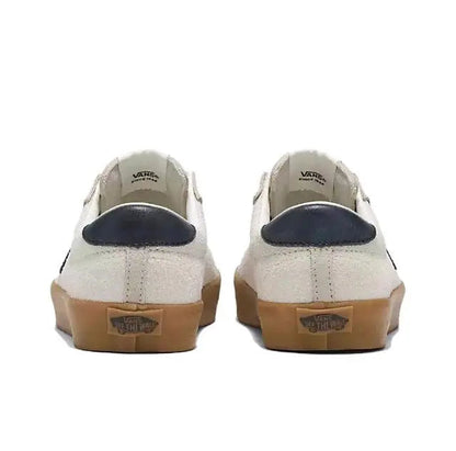 Vans low-top sneakers back view with beige/white uppers, navy heel detail, gum outsole