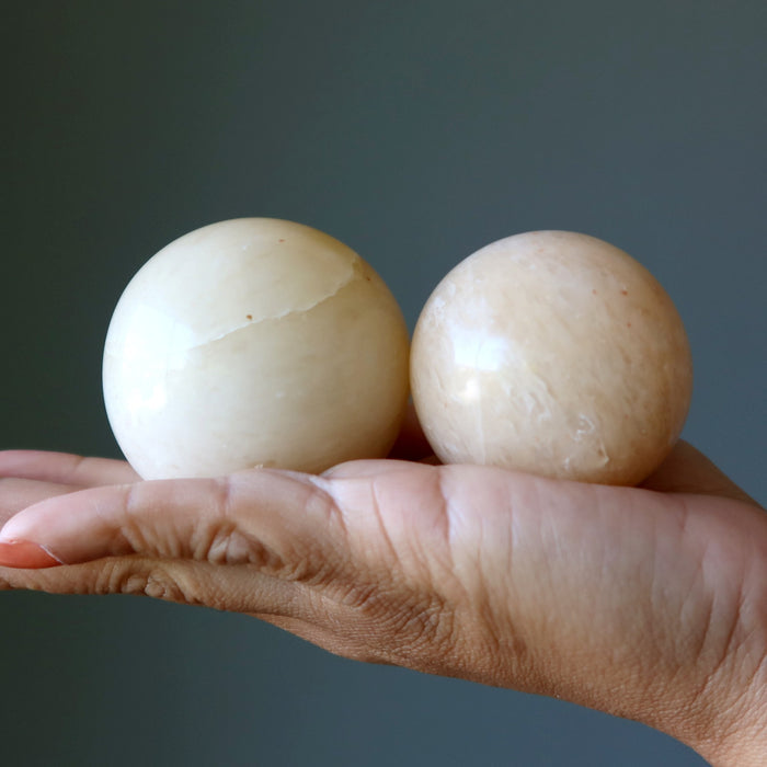 two yellow aventurine spheres in palm of hands