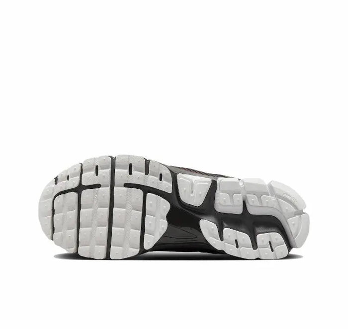 Running shoe sole view with white cushioning pods and dark tread