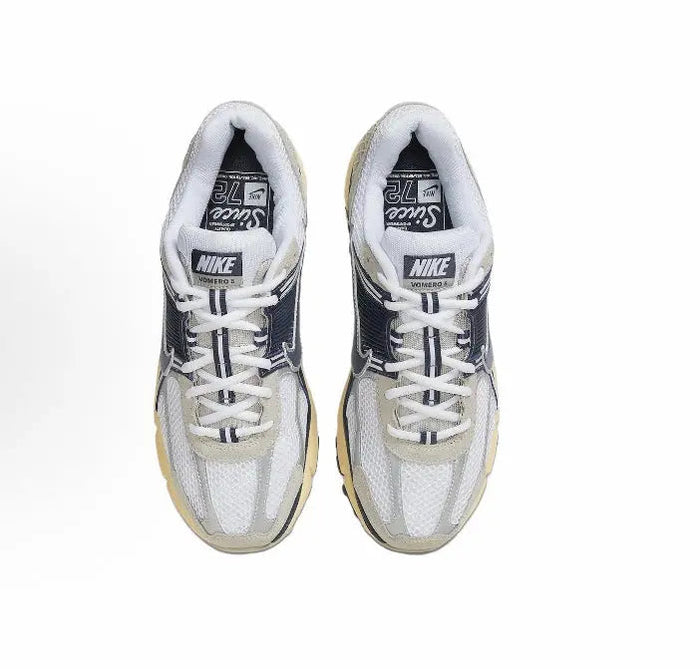 Nike running sneaker pair with white laces, light gray uppers, navy detail on tongue