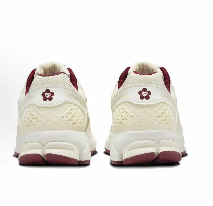 Back view of white Nike running shoe with burgundy heel and flower logo