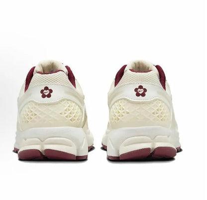 Back view of white Nike running shoe with burgundy heel and flower logo
