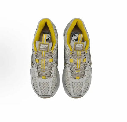 Pair of gray sneakers with yellow interiors, lace-up vamps, and Nike logo