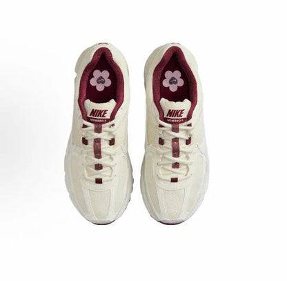 Pair of white Nike sneakers with burgundy lining, laces, and flower emblem