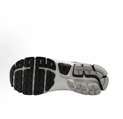 Running shoe outsole view with black tread pods and gray sidewalls