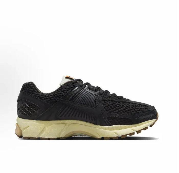 Nike running shoe side view, black textured upper with tan midsole and foam sole