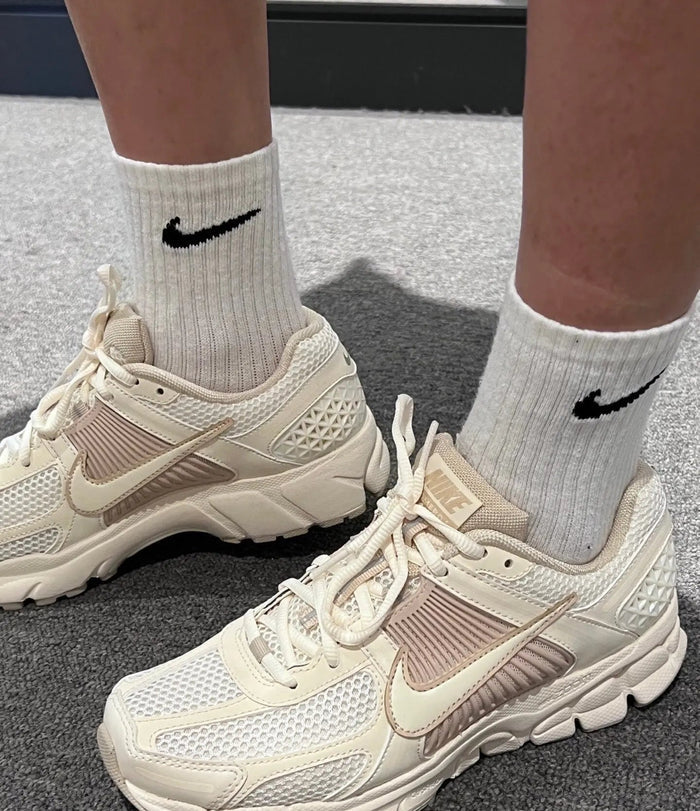Pale ivory running sneakers with Nike Swoosh and white ribbed crew socks
