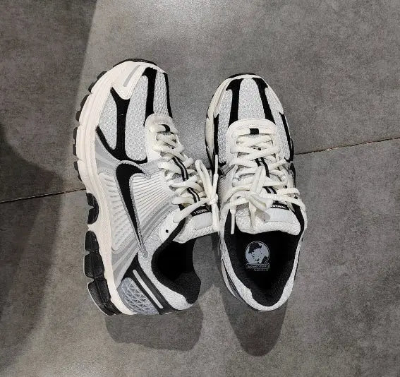 Pair of running sneakers on floor, white laces with black-and-gray side panels