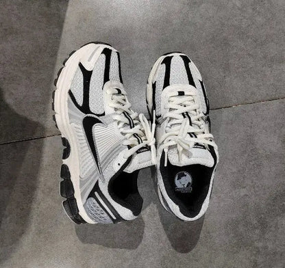 Pair of running sneakers on floor, white laces with black-and-gray side panels