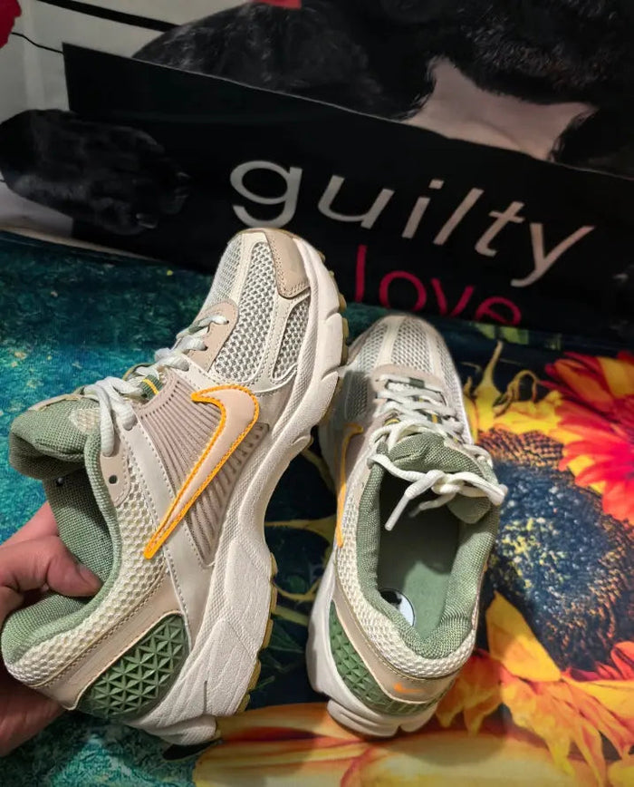 Nike Zoom Vomero 5 SP sneakers held in hand, pale ivory uppers with green heel