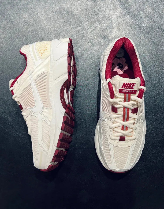 Close-up of white Nike sneakers with burgundy straps and flower detail