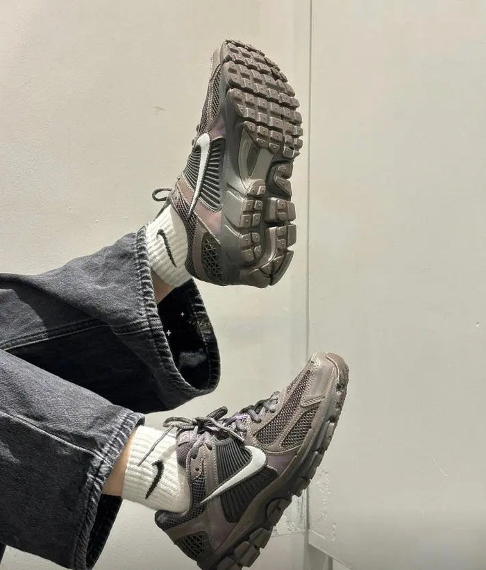 Running shoe on foot, dark gray mesh with blue laces and silver Swoosh