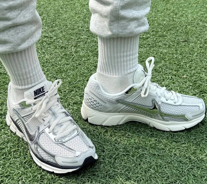 Light gray running shoes with Nike swoosh and white laces, worn with ribbed socks